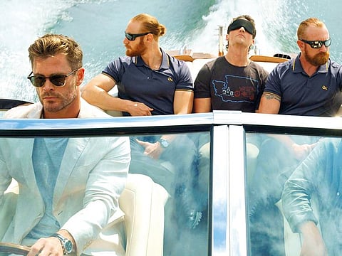 This image released by Netflix shows Chris Hemsworth left, Miles Teller, background center, and Mark Paguio, right, in a scene from "Spiderhead." 