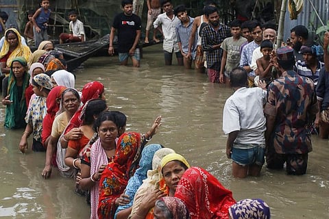 Flood affected people queue in knee-deep flood waters to collect food relief following heavy monsoon rainfalls in Sunamganj on June 21, 2022.
