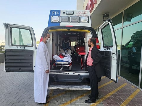Community volunteers Naseer Vatanappally (left) and Kareem Valapad see off Sandheev while he was being transported from the hospital to the airport. 