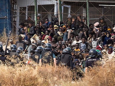 Riot police officers cordon off the area after migrants arrive on Spanish soil and crossing the fences separating the Spanish enclave of Melilla from Morocco in Melilla, Spain, Friday, June 24, 2022.