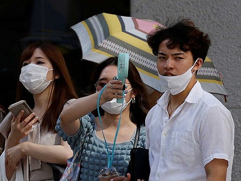 Pedestrians uses a portable fan on the street during a heatwave in Tokyo, Japan, June 27, 2022. 