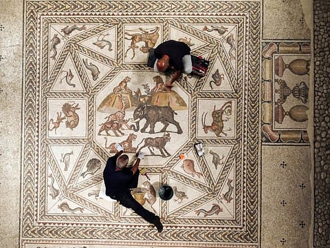 Workers clean a restored Roman-era mosaic after it was put on display at its original site in Lod, now an Israeli city where an archaeological centre has been inaugurated in Lod on June 27, 2022. 