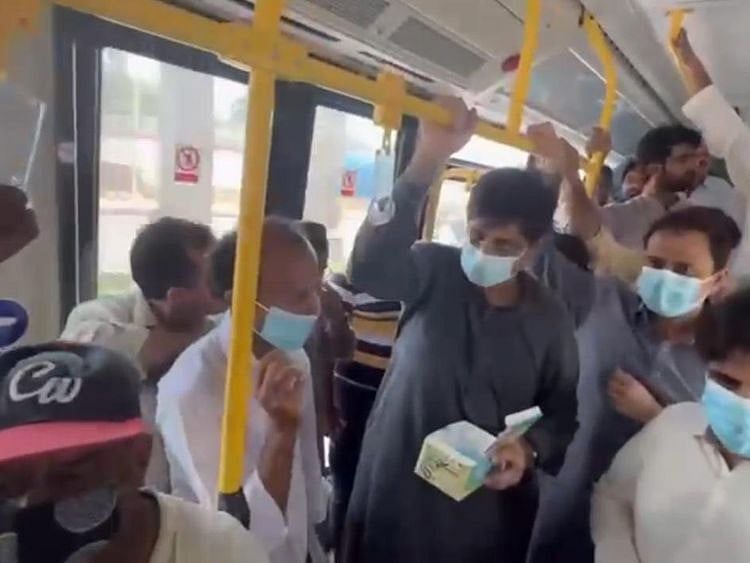 Sindh Chief Minister Syed Murad Ali Shah speaks to a passenger after giving him a mask.