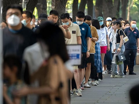 People stand in line for COVID-19 tests at a site in Beijing, Saturday, July 2, 2022. 