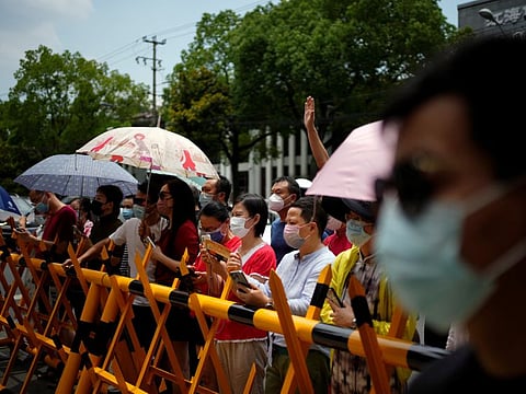 Parents wearing face masks wait for students outside a venue of the annual national "gaokao" university entrance exam, which was postponed in the city due to the coronavirus disease (COVID-19) outbreak, in Shanghai, China July 7, 2022.