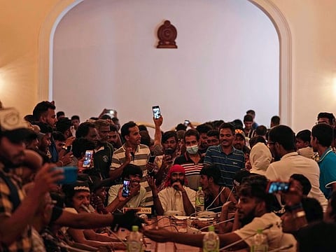Protesters pretend to hold a cabinet meeting after occupying seats at the cabinet meeting hall of president's official residence a day after it was stormed in Colombo, on July 10, 2022. 