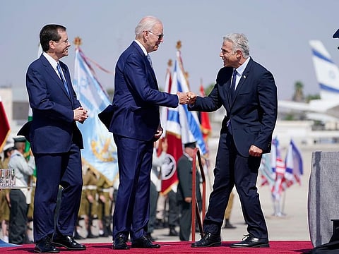 President Joe Biden is greeted by Israeli Prime Minister Yair Lapid, right, and President Isaac Herzog, left, as they participate in an arrival ceremony at Ben Gurion Airport, on July 13, 2022, in Tel Aviv. 
