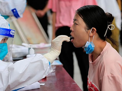 This photo taken on July 13, 2022 shows a health worker taking a swab sample from a woman to be tested for the Covid-19 coronavirus at a residental area in Zhangye in China's northwestern Gansu province.