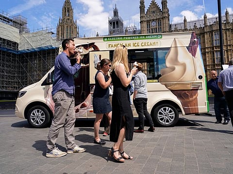 People eat ice cream outside the houses of Parliament, in London.