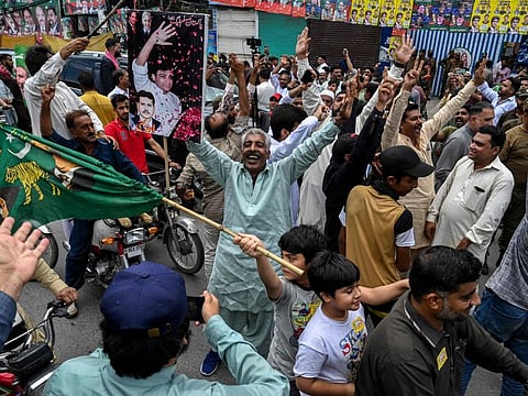 Political activists shout slogans outside a polling station during the by-election in Punjab province assembly seat in Lahore on July 17, 2022.