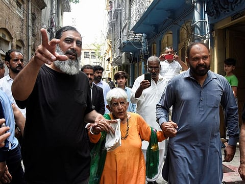 Reena Varma, 92-year-old Indian citizen born in Pakistan, walks with locals along a street, while visiting her ancestral home after 75 years, in Rawalpindi, Pakistan July 20, 2022.