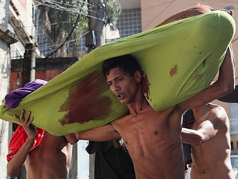 People carry a dead body during a police operation against drug gangs in the Alemao slums complex, in Rio de Janeiro, Brazil, July 21, 2022.