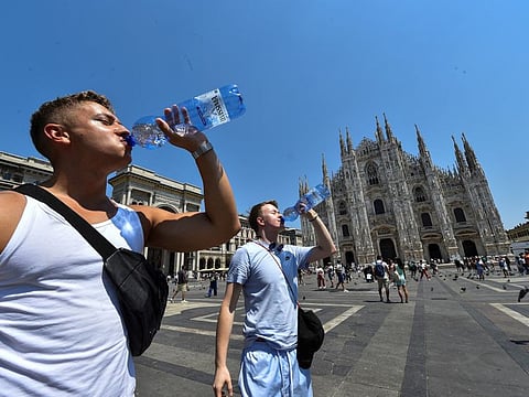 Men drink water by Milan's Duomo cathedral at Duomo square, as temperatures soar during a heatwave in Milan, Italy, July 21, 2022.