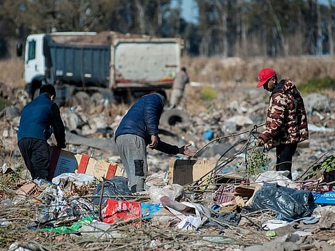 People look for dollar notes among the garbage, in the dump of Las Parejas, Santa Fe province, Argentina on July 20, 2022.