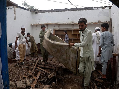 People salvage usable items from their house, after the roof collapsed due to heavy rains, in Peshawar, Pakistan, Thursday, July 28, 2022.