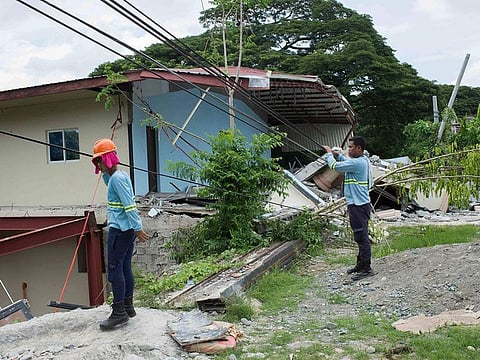 Workers fix electric lines beside a damaged structure a day after a strong quake struck Bangued, Abra province, northern Philippines.