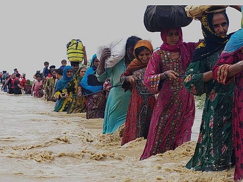 Rescue workers help villagers to evacuate them from flooded area caused by heavy rains, in Lasbella, a district in Pakistan's southwest Baluchistan province, Tuesday, July 26, 2022.