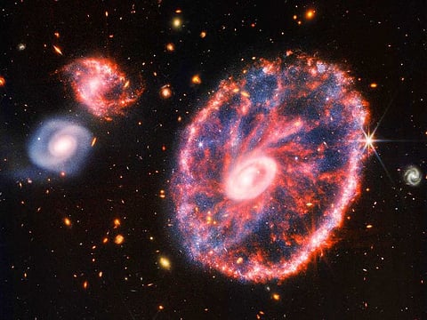 This handout composite image by ESA/Webb relased on August 2, 2022 shows the Cartwheel and its companion galaxies is a composite from Webb’s Near-Infrared Camera (NIRCam) and Mid-Infrared Instrument (MIRI), which reveals details that are difficult to see in the individual images alone.