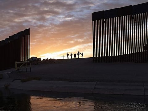 In this Thursday, June 10, 2021, file photo, a pair of migrant families from Brazil pass through a gap in the border wall to reach the United States after crossing from Mexico to Yuma, Ariz., to seek asylum.