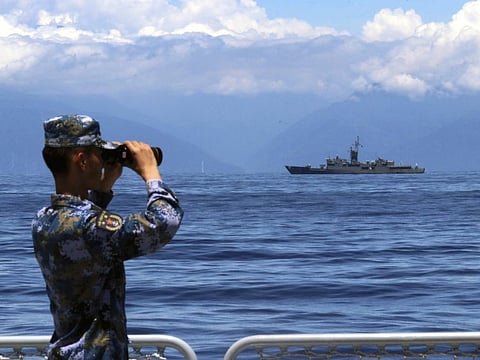 In this photo provided by China’s Xinhua News Agency, a People's Liberation Army member looks through binoculars during military exercises as Taiwan’s frigate Lan Yang is seen at the rear, on Friday, Aug. 5, 2022.