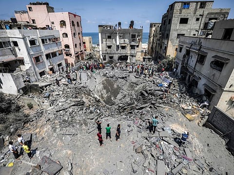 Palestinians inspect the ruins of a collapsed building destroyed by an Israeli air strike in Gaza City, on August 6, 2022.
