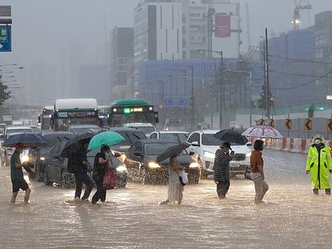 Pedestrians cross a flooded road at a junction in Gimpo, South Korea, on Tuesday, Aug. 9, 2022.