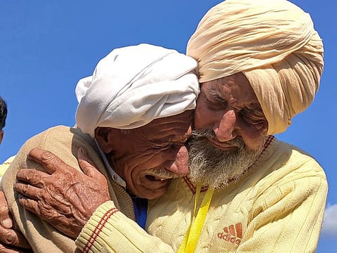 This handout picture taken on January 12, 2022 and received as a courtesy of Pakistan's Youtuber Nasir Dhillon shows Indian Sikh labourer Sika Khan (R) embracing his elder brother Sadiq Khan from Pakistan near the India-Pakistan border at the Kartarpur corridor.