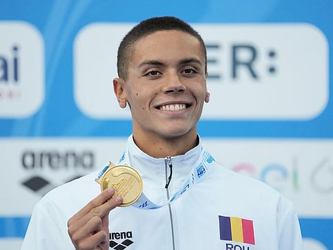First placed Romania's David Popovici celebrates on the podium of the men's 100m freestyle final at the European swimming championships, in Rome, on August 13, 2022. 