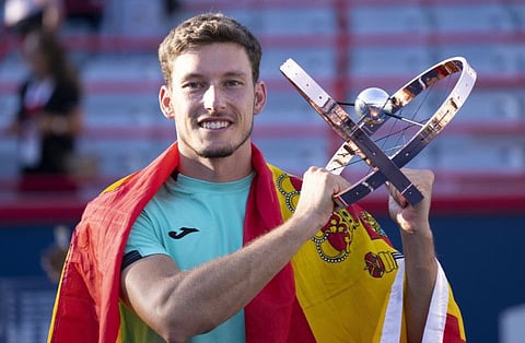 Pablo Carreno Busta, of Spain, hoists the trophy as he celebrates after defeating Hubert Hurkacz, of Poland, in the final of the National Bank Open tennis tournament in Montreal.