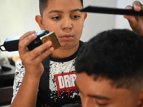 Eduardo Espinal cuts the hair of a client at his barbershop.