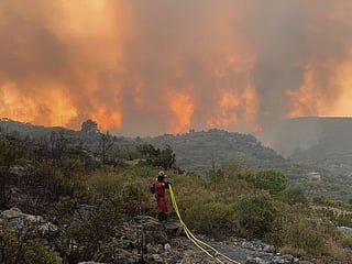 File: A Military Emergency Unit personnel works to extinguish a forest fire in Useres, eastern Spain, on August 15, 2022. 