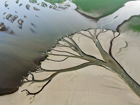 In this aerial photo released by China's Xinhua News Agency, water flows through channels in the lake bed of Poyang Lake, China's largest freshwater lake, in eastern China's Jiangxi Province, on Aug. 22, 2022.  
