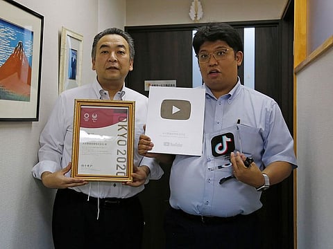Daikyo Security Chief Executive Daisuke Sakurai, right, and General Manager Tomohiko Kojima hold the awards they have won recently for their Tik Tok videos in the hallway of their Tokyo headquarters office of Daikyo Security Co. in Tokyo Monday, Aug. 22, 2022.