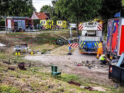 Emergency services operate at the scene of an accident after a lorry drove off a dike into a neighborhood party.