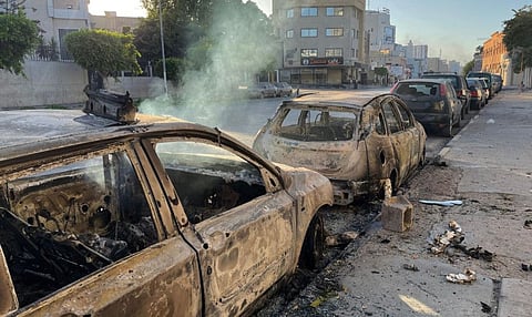 Damaged vehicles are pictured in a street in the Libyan capital Tripoli on August 27, 2022.