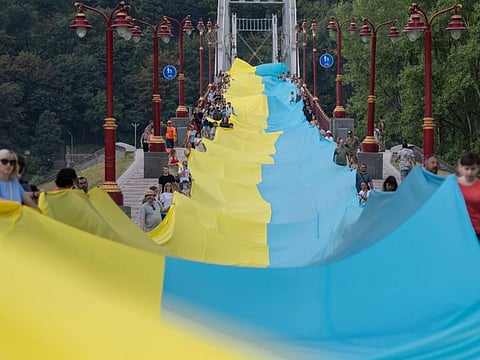 Activists hold a giant Ukrainian flag during an event "Ukraine united" in Kyiv, on August 28, 2022. The action symbolises the unity of the Ukrainian people in the struggle for the independence of Ukraine. The 430-meter long flag connected both sides of Dnipro river. 