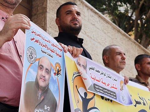 People hold pictures of Mohammad Al Halabi, during a solidarity gathering following an Israeli court decision to sentence him for 12 years, outside the office of the International Committee of the Red Cross in Gaza City August 30, 2022. 