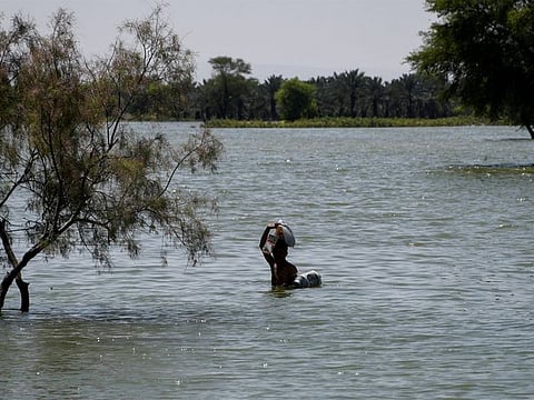 A flood victim wades through flood water, following rains and floods during the monsoon season in Bajara village, Sehwan, Pakistan, on August 31, 2022. 