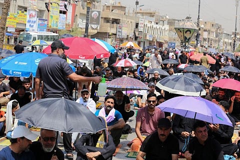 A man sprays water to cool down supporters of Iraq's Shiite cleric Moqtada Sadr as they listen to the sermon following Friday prayers in Sadr City in eastern Baghdad, on September 2, 2022. 