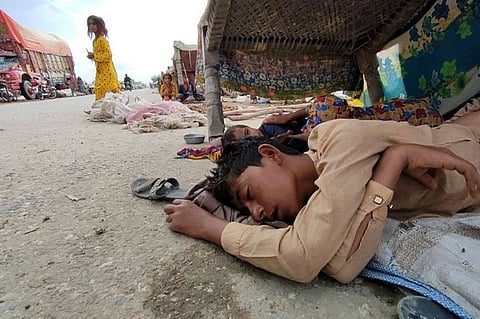 In this picture taken on September 2, 2022 internally displaced flood affected children sleep under a charpai as they take refuge in Bolan district, Balochistan province.  