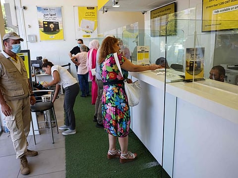 Employees serve customers at a money transfer office in Lebanon's capital Beirut, on July 27, 2022.
