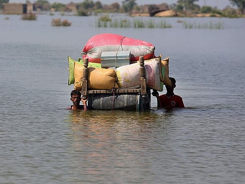 Flood-affected people use cot to salvage belongings from their nearby flooded home caused by heavy rain, in Qambar Shahdadkot district of Sindh Province, of Pakistan
