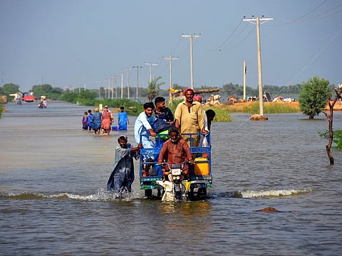 Flood-affected people use cot to salvage belongings from their nearby flooded home in Qambar Shahdadkot district of Sindh Province.