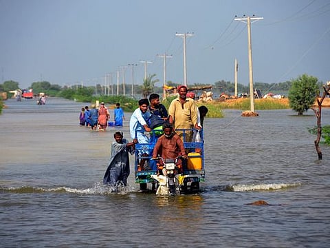 Flood-affected people use cot to salvage belongings from their nearby flooded home in Qambar Shahdadkot district of Sindh Province.