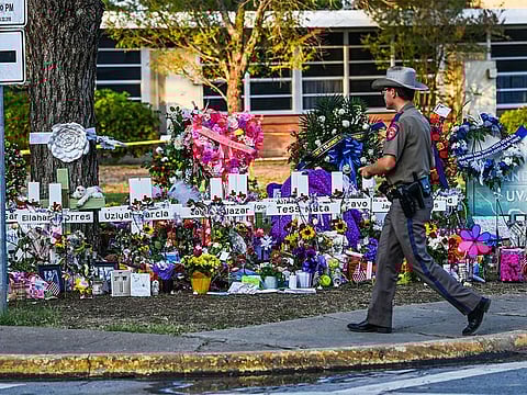 A police officer walks near the makeshift memorial for the shooting victims outside Robb Elementary School in Uvalde, Texas.