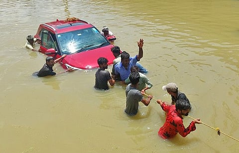 People pull a car through a water-logged road following torrential rains in Bengaluru, India, September 5, 2022.