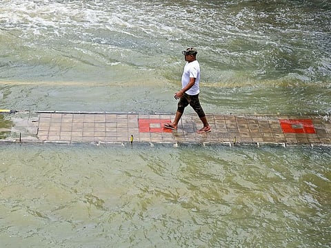 A man walks over an inundated footpath following heavy rains, in Bengaluru on Wednesday, September 7, 2022.