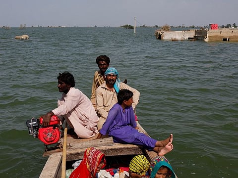 Residents ride on a boat as they pass submerged houses amid flood water, following rains and floods during the monsoon season in Bajara village, at the banks of Manchar lake, in Sehwan, Pakistan September 6, 2022. 