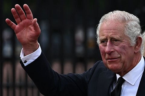Britain's King Charles III waves as he walks into Buckingham Palace after greeting the crowd and looking at floral tributes, in London, on September 9, 2022.