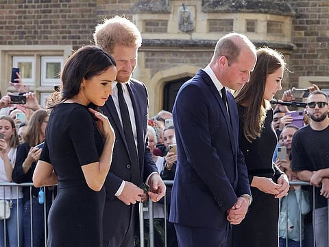 From left: Britain's Prince Harry and Meghan, Duchess of Sussex (left), and Britain's Prince William and Kate, Princess of Wales, look at floral tributes laid by members of the public on the Long walk at Windsor Castle on September 10, 2022, before meeting well-wishers. 